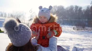 女孩在冬天阳光明媚的时候和宝宝玩。 双手紧握